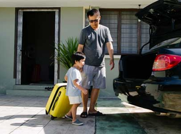 father and son loading car with suitcase